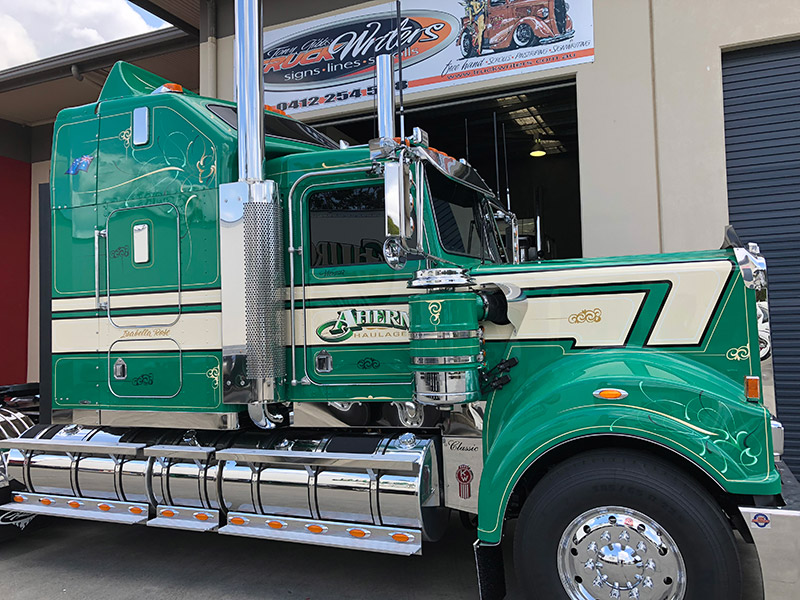 Green Kenworth with Ahern Haulage lettering and cream stripes, parked outside the Truck Writers workshop